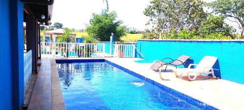 a swimming pool with two chairs next to a blue wall at Temporada Belas Casas in São Pedro