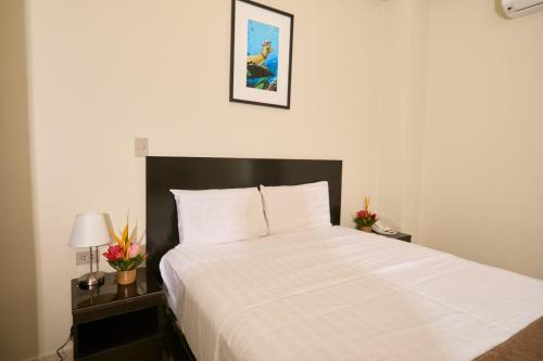 a bedroom with a white bed with a black headboard at Hotel Marañón in Iquitos