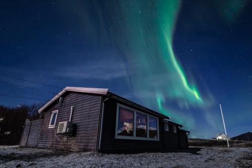 a house with the aurora in the sky at Cozy cabin by the sea in Tromsø