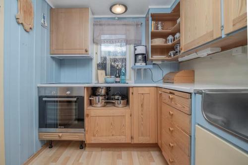 a kitchen with wooden cabinets and a stove top oven at Cozy cabin by the sea in Tromsø
