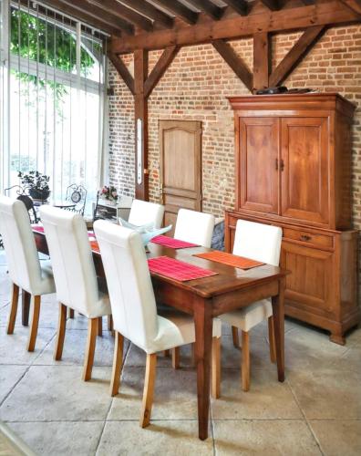 une salle à manger avec une table en bois et des chaises blanches dans l'établissement Maison charmante au Vaudreuil avec magnifique jardin clos, à Le Vaudreuil