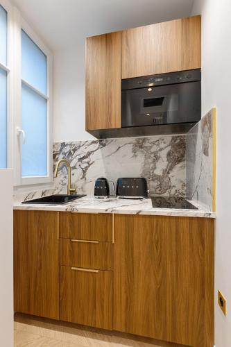 une cuisine avec un évier et un micro-ondes dans l'établissement Serviced Apartment - 6 Guests - Champs-Élysées, à Paris