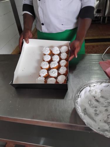 a person holding a box of cupcakes on a counter at SILVER SLOPES RESORT AND SPA in Kagio