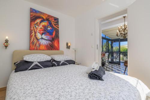 a bedroom with a bed with a painting on the wall at Jacaranda Cottage in Malinska