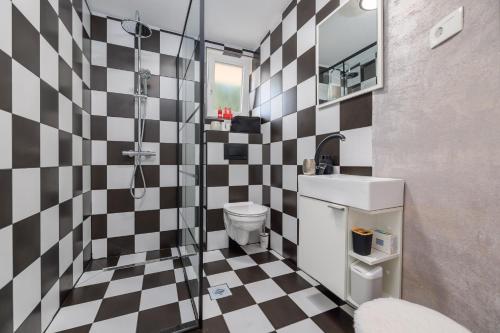 a bathroom with a black and white checkered wall at Jacaranda Cottage in Malinska