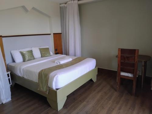 a bedroom with a large bed and a chair at SILVER SLOPES RESORT AND SPA in Kagio