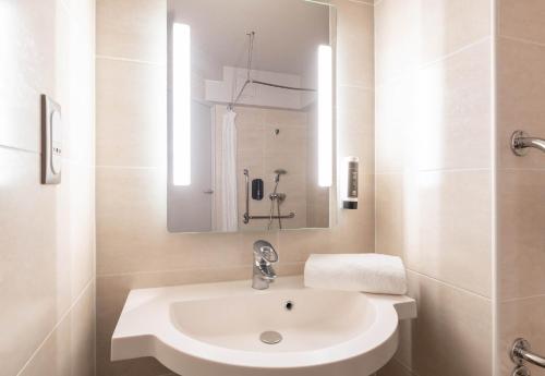 Un baño blanco con lavabo y espejo. en B&B HOTEL Lyon Vénissieux, en Vénissieux