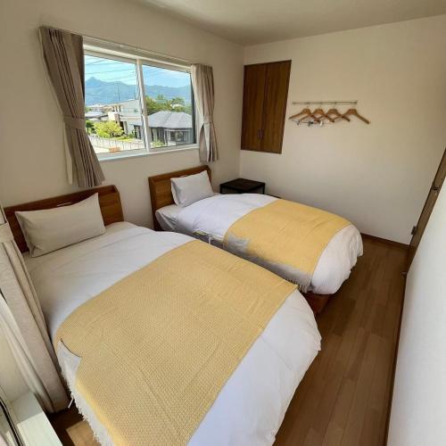 two beds in a small room with a window at Villa ANOTONA No 1 in Fujikawaguchiko