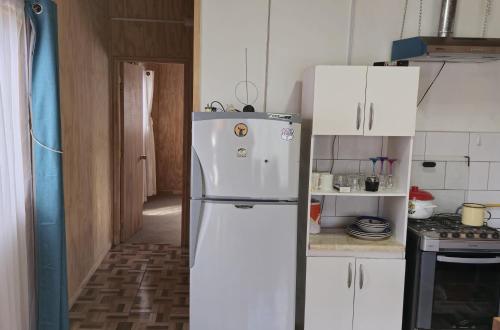 a white refrigerator in a kitchen with white cabinets at departamento el coiron in Cochrane