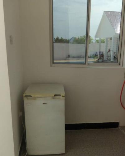 a small white refrigerator in a room with a window at KATALE Villa in Jambiani