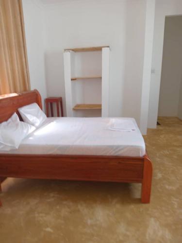 a bedroom with a wooden bed with white sheets at KATALE Villa in Jambiani