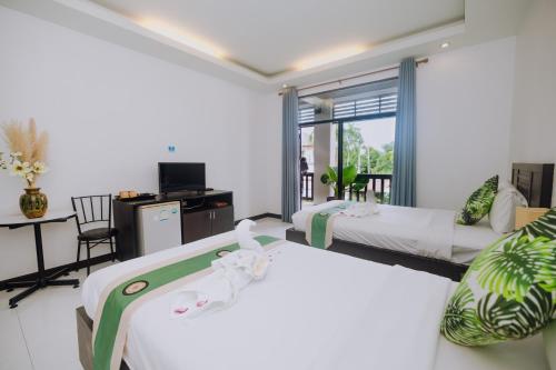 a hotel room with two beds and a tv at Monaburi Boutique Resort in Rawai Beach