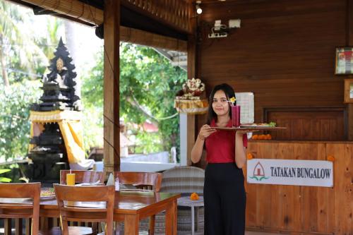 a woman is holding a plate of food at Kelingking Tatakan Bungalow in Nusa Penida