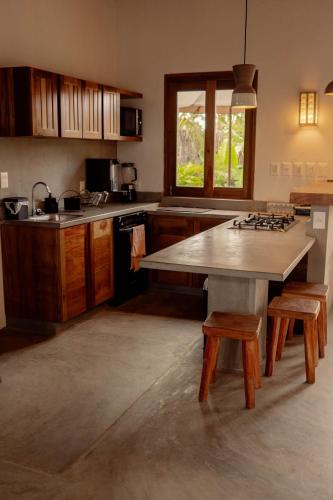 a kitchen with a large table and wooden cabinets at Teça Suites in Guriú