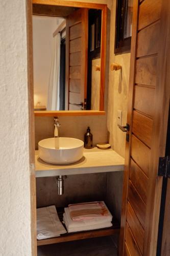 a bathroom with a sink and a mirror at Teça Suites in Guriú