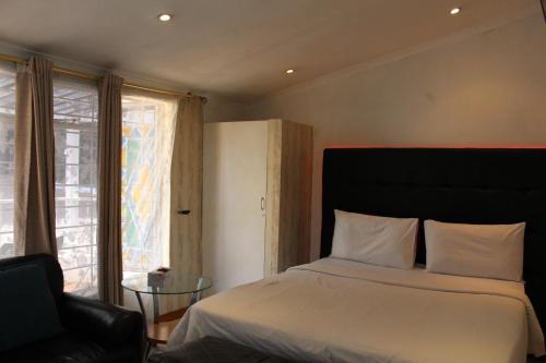 a bedroom with a bed and a chair and a window at Isabels2 Guest house in Johannesburg