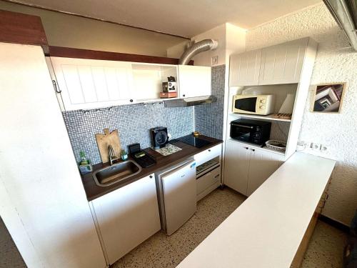 une petite cuisine avec un évier et un micro-ondes dans l'établissement Appartement 2 pièces - Port La Nouvelle PN590-025, à Port-la-Nouvelle