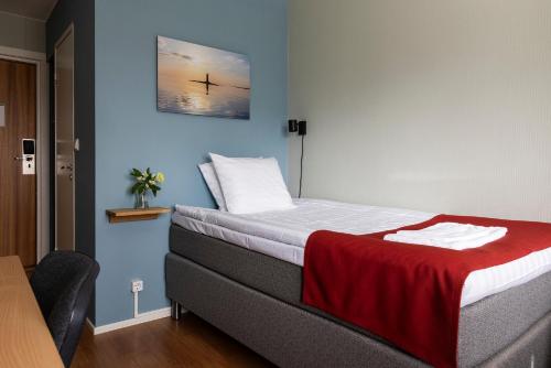 a bedroom with a bed with a red blanket on it at Strandnäs Hotell in Mariehamn