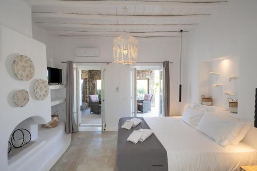 a white bedroom with a large bed and a chandelier at Ambiente Villas 3Βd-Agios Ioannis in Agios Ioannis Mykonos
