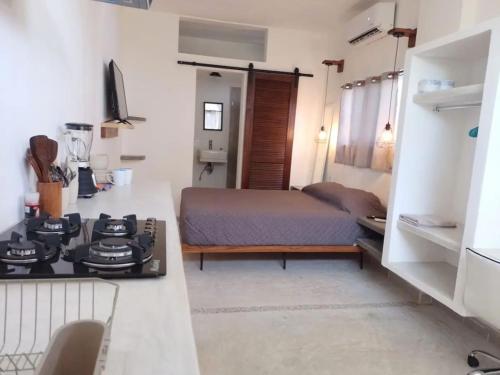 a kitchen with a bed and a stove in a room at Shaka Studio - steps to beach in Punta Mita