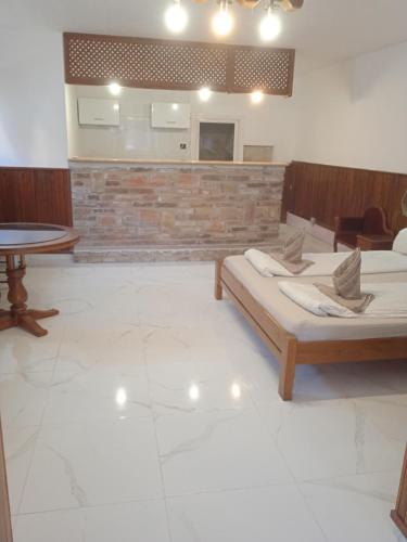 a room with two beds and a table in it at R4 Rolléder Apartman-ház in Siklós