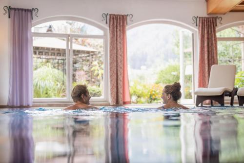 a man and a woman in a swimming pool at Familien- & Vitalhotel Auenhof in Fulpmes