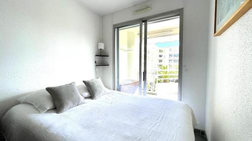 un lit blanc dans une chambre avec une fenêtre dans l'établissement Incroyable vue mer et accès plage !, à Antibes