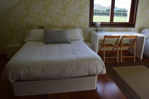 a bedroom with a bed and a table and a window at Casa Aida in Foz