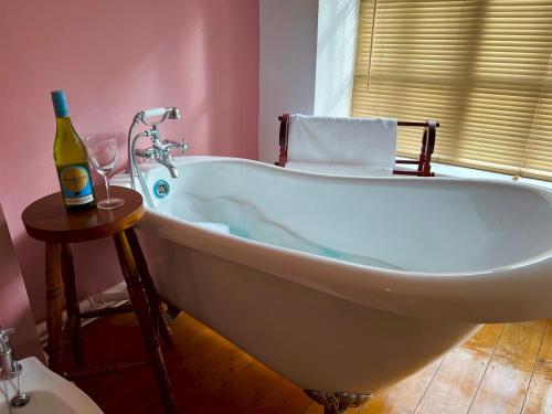 a bath tub in a bathroom with a bottle of wine at Dene Cottage - Perfect for 8 & Pets in Youlgrave - Pass the Keys in Youlgreave