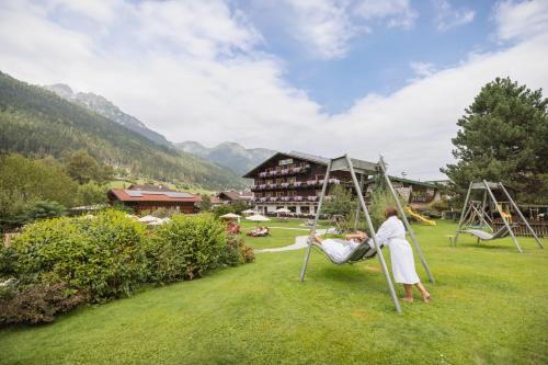 a woman sitting on a swing in a park at Familien- & Vitalhotel Auenhof in Fulpmes