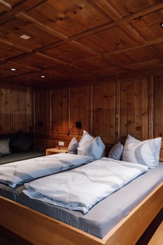 a large bed in a room with wooden walls at Haus Saler in Gaschurn