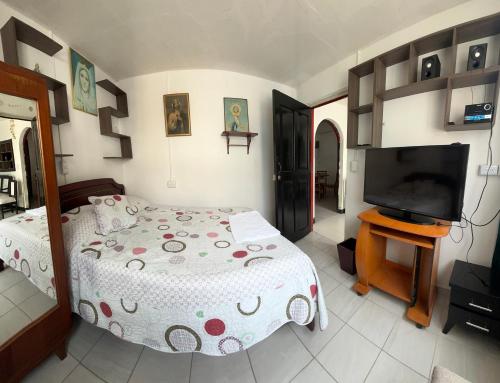 Un dormitorio con una cama y un televisor de pantalla plana. en Carana, en Paipa