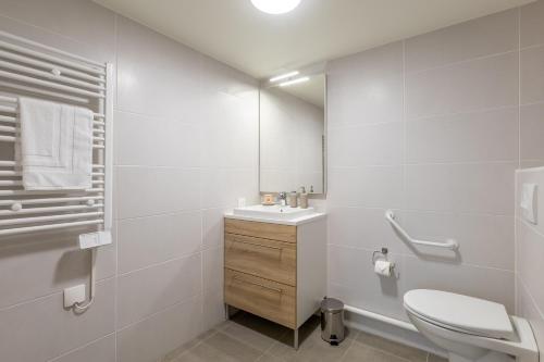 a white bathroom with a sink and a toilet at OVELIA Ermont - Le Pavillon d'Amélie in Ermont
