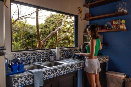 a woman standing in a kitchen looking out a window at Beautiful Ocean View 4BR Casa with 5 Star Concierge in Sayulita