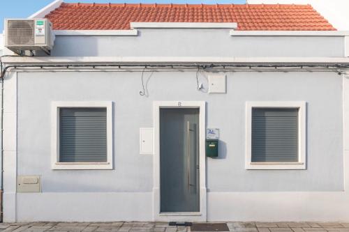 a white house with a door and a red roof at Casa do Pátio do Tejo Nº8 in Sarilhos Pequenos