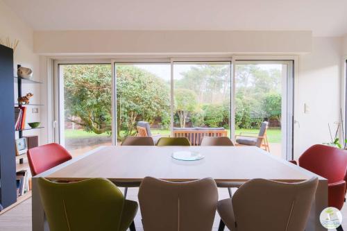 une pièce avec une table et des chaises et une grande fenêtre dans l'établissement Biscarrosse Plage Maison de charme proche des plages océanes classé 1, à Biscarrosse