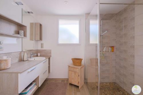 une salle de bain avec une douche en verre et un lavabo dans l'établissement Biscarrosse Plage Maison de charme proche des plages océanes classé 1, à Biscarrosse
