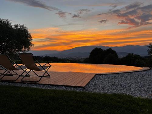 two chairs and a swimming pool at sunset at GATTO IN VIGNA in Susegana