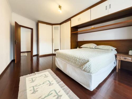 a bedroom with a white bed and a wooden floor at Casa espaçosa a apenas 30 minutos de SP in Sao Paulo