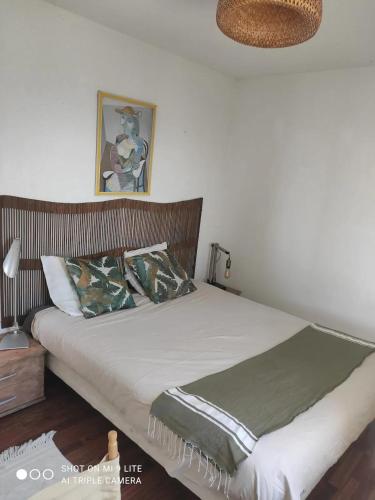 une chambre avec un grand lit avec une tête de lit en bois dans l'établissement Appartement moderne à Ajaccio avec vue sur la mer, à Ajaccio