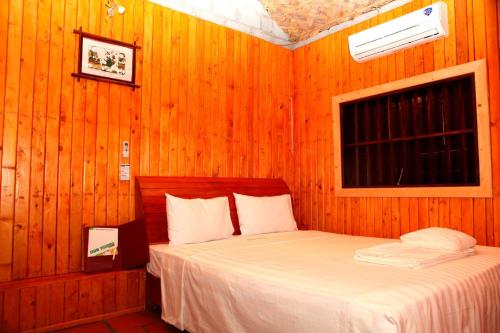 1 dormitorio con 1 cama en una pared de madera en Whisper Nature Bungalow & Resort, en Cat Ba