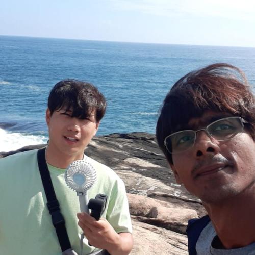 two men standing next to the ocean with a microphone at Guest house weherahena in Matara