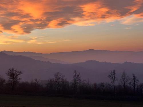 a sunset over a mountain range with trees in the foreground at B&B Casa dei Cuori - Natura, Silenzio, relax a 550 m di quota in Langhirano