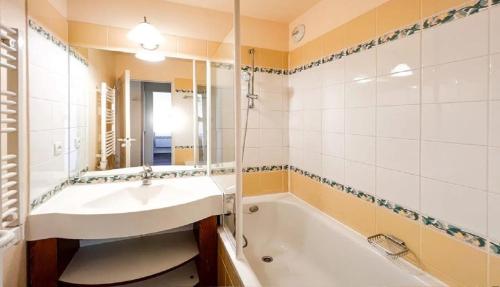 une salle de bain avec un lavabo, une baignoire et un miroir dans l'établissement Nid des Cimes, à Valmeinier