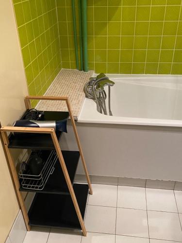 La salle de bains est pourvue d'une baignoire blanche et de carrelage vert. dans l'établissement Tourgeville residence de standing, à Tourgéville