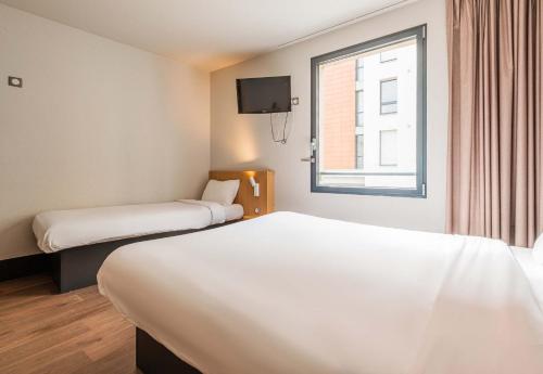 a hotel room with two beds and a window at B&B HOTEL Mulhouse Centre in Mulhouse
