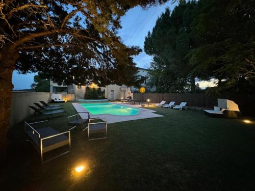 a backyard with a swimming pool with chairs and a tree at Belle Lauragaise ensoleillée in Issel