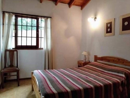 圣贝尔纳多Departamento de 2 ambientes y medio c/entrada de auto的一间卧室配有一张带条纹毯子的床和窗户