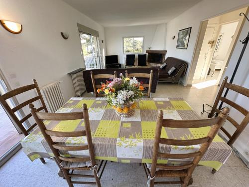 une table de salle à manger avec un vase de fleurs dessus dans l'établissement Haut de villa, pleine vue mer, à Saint-Mandrier-sur-Mer