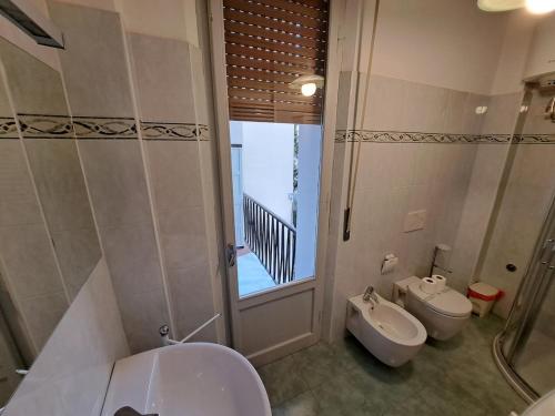 Un baño con dos lavabos y un inodoro y una ventana. en The Cesare, en Parma